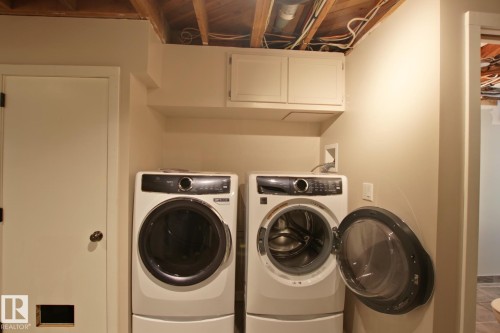 Laundry area featuring wall-mounted cabinetry and painted walls - 5712 113B Street Nw, Edmonton, AB - Indoor Photo Showing Laundry Room