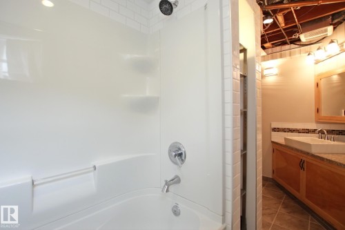 White shower-over-tub combination with subway tile surround and rain showerhead - 5712 113B Street Nw, Edmonton, AB - Indoor Photo Showing Bathroom