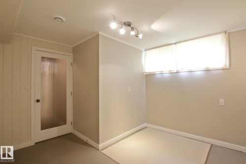 Recessed ceiling lighting, track lighting fixture, glass-panel interior door, and paneling accent wall - 5712 113B Street Nw, Edmonton, AB - Indoor Photo Showing Other Room