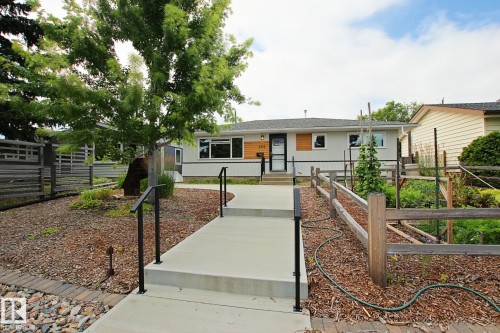 Modern exterior with light gray siding, wood-look accents, and dark trim windows - 5712 113B Street Nw, Edmonton, AB - Outdoor