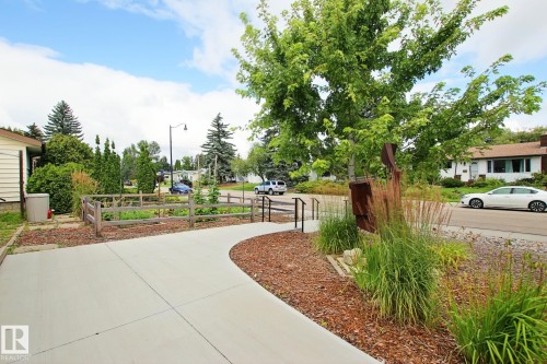 Concrete driveway with a curved pathway, bordered by wood mulch landscaping, a split-rail fence, and mature trees - 5712 113B Street Nw, Edmonton, AB - Outdoor