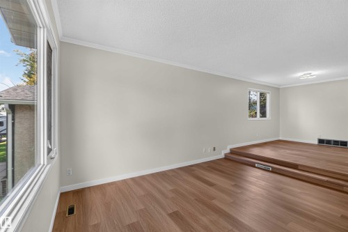 Wood-finish flooring throughout, light neutral wall paint, and white crown molding - 14725 43A Avenue Nw, Edmonton, AB - Indoor Photo Showing Other Room