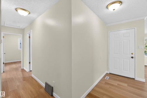 Wood-finish flooring, neutral wall paint, white trim, and a white paneled door - 14725 43A Avenue Nw, Edmonton, AB - Indoor Photo Showing Other Room