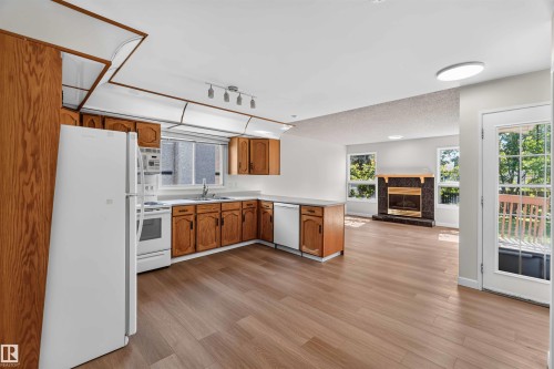 Full kitchen with wood cabinetry, light countertops, and white appliances - 14725 43A Avenue Nw, Edmonton, AB - Indoor Photo Showing Kitchen With Double Sink