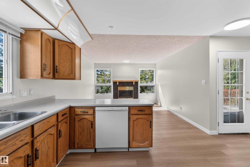 Kitchen with wood cabinetry, light-colored countertops, and a stainless steel sink - 14725 43A Avenue Nw, Edmonton, AB - Indoor Photo Showing Kitchen With Double Sink
