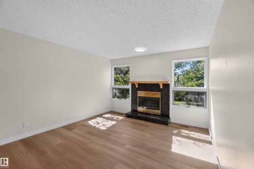 Wood-finish flooring, white walls, and a recessed ceiling light - 14725 43A Avenue Nw, Edmonton, AB - Indoor Photo Showing Living Room With Fireplace