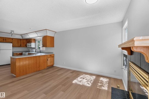 Kitchen area featuring wood cabinetry, white appliances, and a peninsula - 14725 43A Avenue Nw, Edmonton, AB - Indoor Photo Showing Kitchen With Double Sink