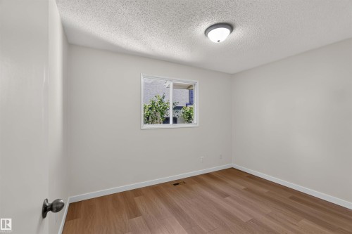 Neutral wall tones, wood-finish flooring, white trim, and a window for natural light - 14725 43A Avenue Nw, Edmonton, AB - Indoor Photo Showing Other Room