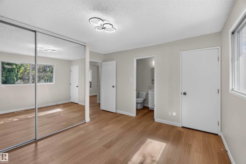 Wood-finish flooring, mirrored closet doors, a contemporary ceiling light fixture, and white trim throughout - 14725 43A Avenue Nw, Edmonton, AB - Indoor Photo Showing Other Room