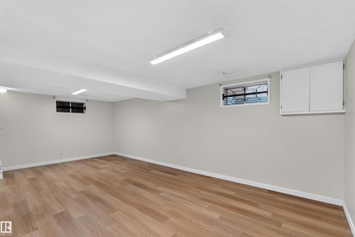 Spacious room featuring wood-finish flooring, light gray walls, built-in cabinetry, and multiple windows - 14725 43A Avenue Nw, Edmonton, AB - Indoor