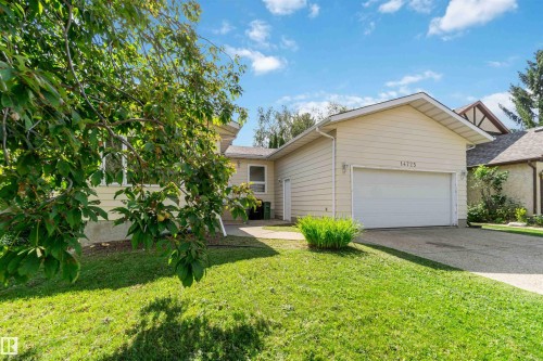 Cream-colored siding exterior, attached garage, concrete driveway, and front lawn - 14725 43A Avenue Nw, Edmonton, AB - Outdoor