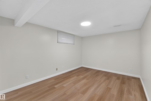 Light-toned walls with wood-finish flooring, featuring a recessed ceiling light, an overhead beam, and a single window with blinds - 14725 43A Avenue Nw, Edmonton, AB - Indoor Photo Showing Other Room