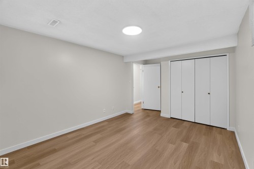 Wood-finish flooring, recessed ceiling lighting, bi-fold closet doors, and white trim - 14725 43A Avenue Nw, Edmonton, AB - Indoor Photo Showing Other Room