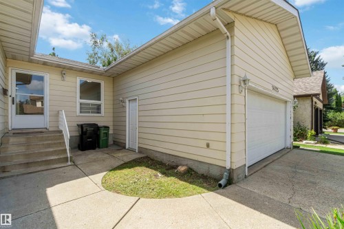 Siding exterior with a concrete pathway and steps, attached garage, and a side entry door - 14725 43A Avenue Nw, Edmonton, AB - Outdoor With Exterior