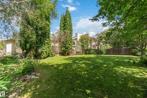Expansive lawn with mature landscaping, wood fencing, and a multi-level wood deck - 14725 43A Avenue Nw, Edmonton, AB - Outdoor