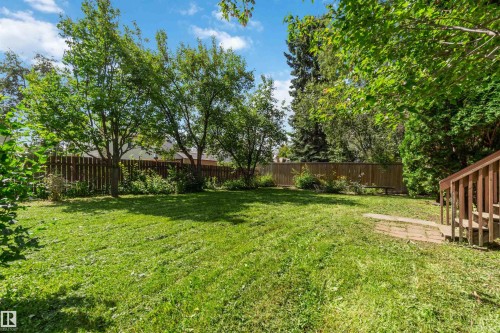 Expansive green lawn surrounded by mature trees, privacy fencing, and garden beds - 14725 43A Avenue Nw, Edmonton, AB - Outdoor