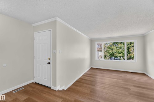 Hardwood-style flooring, white trim, and a window framing mature trees - 14725 43A Avenue Nw, Edmonton, AB - Indoor