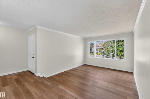 Expansive room featuring wood-finish flooring, white trim, and a large multi-pane window - 14725 43A Avenue Nw, Edmonton, AB - Indoor