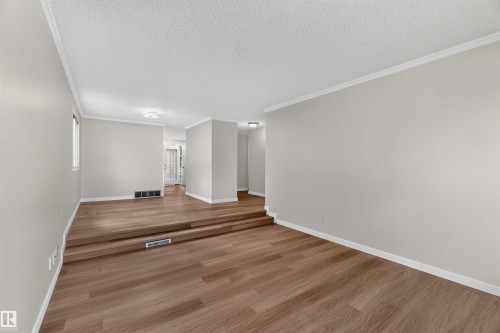 Multi-level layout with wood-finish flooring, white crown molding, and neutral wall tones - 14725 43A Avenue Nw, Edmonton, AB - Indoor Photo Showing Other Room