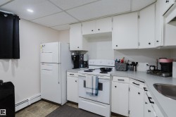Kitchen featuring white cabinetry, a white refrigerator, a white electric range, a stainless steel sink, and gray countertops - 