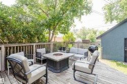 Expansive wood deck featuring a fire pit, wood railing, and surrounding mature trees - 