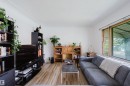 Bright living area featuring wood-finish flooring, a large window with natural wood trim, white painted walls, and textured ceiling - 8759 78 Avenue Nw, Edmonton, AB  - Indoor Photo Showing Living Room 