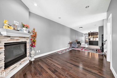Stone-clad fireplace with a classic white mantel - 12730 118 Street Nw, Edmonton, AB - Indoor Photo Showing Living Room With Fireplace