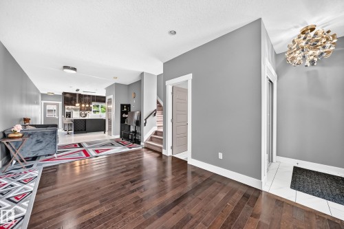 Rich wood-finish flooring, staircase with wood handrail, modern overhead lighting, and built-in shelving - 12730 118 Street Nw, Edmonton, AB - Indoor