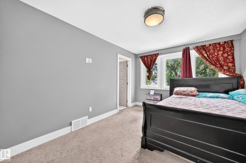 Wall-to-wall carpeting, multiple windows, and a flush-mount ceiling light fixture - 12730 118 Street Nw, Edmonton, AB - Indoor Photo Showing Bedroom