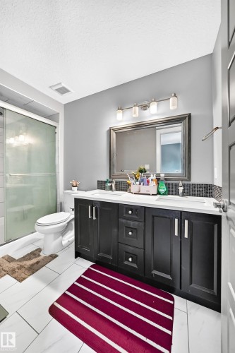 Dual sink vanity with dark wood-finish cabinetry, white countertops, and chrome fixtures - 12730 118 Street Nw, Edmonton, AB - Indoor Photo Showing Bathroom