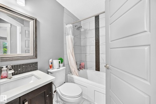 Bathroom featuring a vanity with dark wood-finish cabinetry, white countertop, and mosaic tile backsplash - 12730 118 Street Nw, Edmonton, AB - Indoor Photo Showing Bathroom