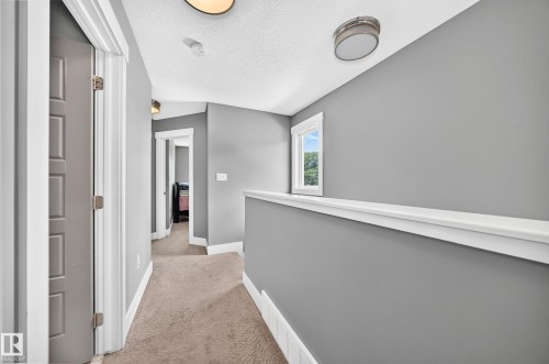 Hallway featuring neutral-toned carpet, gray painted walls, a window with white trim, and flush-mount ceiling lighting - 12730 118 Street Nw, Edmonton, AB - Indoor Photo Showing Other Room