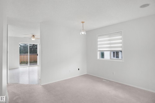 Neutral wall paint, carpet flooring, a window with horizontal blinds, and a built-in ceiling light fixture - 907 Jordan Crescent Nw, Edmonton, AB - Indoor Photo Showing Other Room