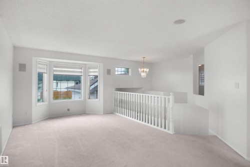 Bay window with shades, light-toned wall-to-wall carpeting, recessed ceiling lighting, decorative chandelier, and white banister - 907 Jordan Crescent Nw, Edmonton, AB - Indoor Photo Showing Other Room