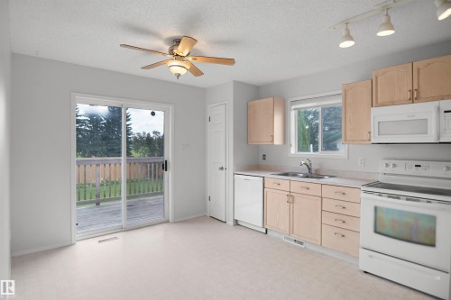 Light-toned cabinetry with coordinating countertops, white appliances, and a double-basin stainless steel sink - 907 Jordan Crescent Nw, Edmonton, AB - Indoor Photo Showing Kitchen With Double Sink