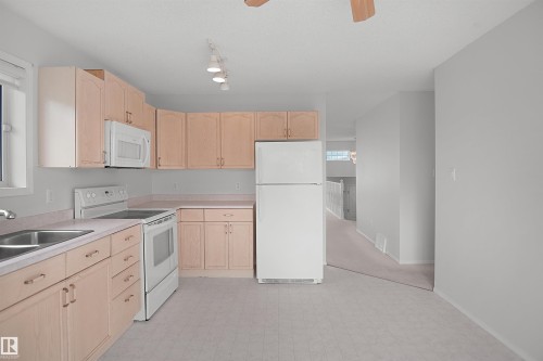 Kitchen featuring wood-finish cabinetry, built-in microwave, electric range, and stainless steel sink - 907 Jordan Crescent Nw, Edmonton, AB - Indoor Photo Showing Kitchen With Double Sink
