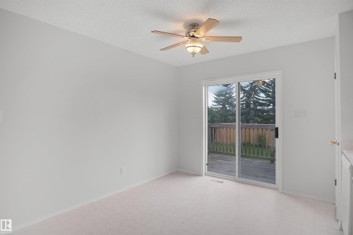 Sliding glass door leading to an outdoor deck, overhead ceiling fan with lighting, and light-toned wall paint - 907 Jordan Crescent Nw, Edmonton, AB - Indoor Photo Showing Other Room