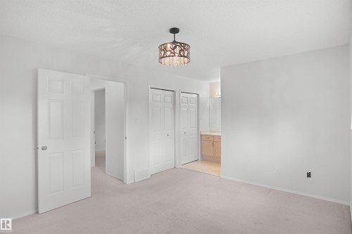 Recessed panel doors, ceiling-mounted chandelier, bi-fold closet doors, wall-to-wall carpeting, and an adjacent vanity with wood-finish cabinetry - 907 Jordan Crescent Nw, Edmonton, AB - Indoor Photo Showing Other Room