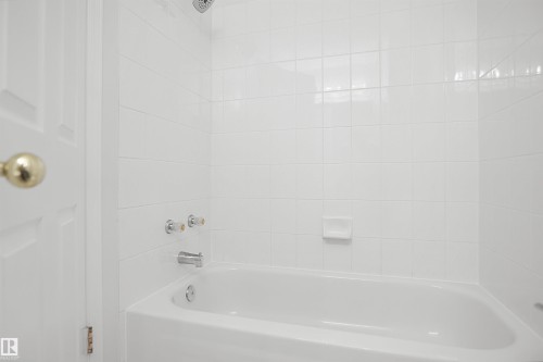 White tiled shower enclosure with a built-in bathtub and chrome fixtures - 907 Jordan Crescent Nw, Edmonton, AB - Indoor Photo Showing Bathroom