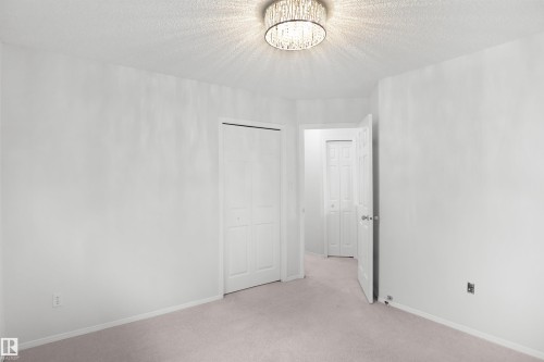 Recessed lighting with a decorative fixture, light-toned carpeting, and a bi-fold closet door - 907 Jordan Crescent Nw, Edmonton, AB - Indoor Photo Showing Other Room