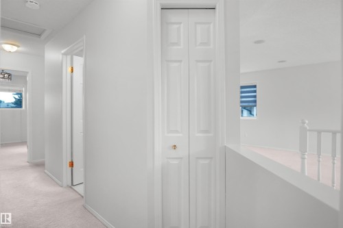White interior walls, traditional bi-fold closet door, white baluster railing, flush mount ceiling lighting, and carpeted flooring - 907 Jordan Crescent Nw, Edmonton, AB - Indoor Photo Showing Other Room