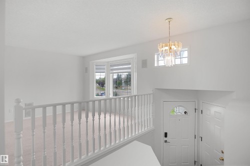 Recessed bay window, decorative chandelier, white spindle railing, paneled entry door with arched glass insert, secondary door - 907 Jordan Crescent Nw, Edmonton, AB - Indoor Photo Showing Other Room