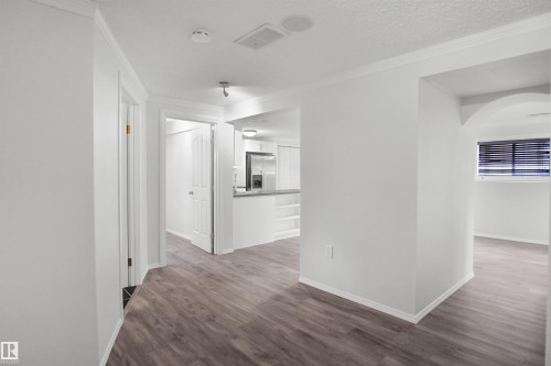 Wood-finish flooring throughout, bright white walls, and crown molding - 907 Jordan Crescent Nw, Edmonton, AB - Indoor Photo Showing Other Room