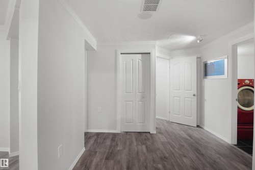 Wood-finish flooring throughout, bright white walls, and multiple white panel doors - 907 Jordan Crescent Nw, Edmonton, AB - Indoor