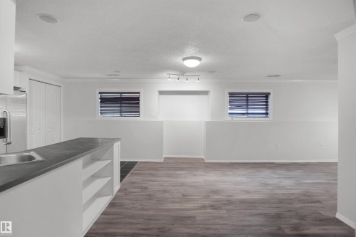 Open-concept living area featuring wood-finish flooring, recessed lighting, and a built-in kitchen island with shelving - 907 Jordan Crescent Nw, Edmonton, AB - Indoor