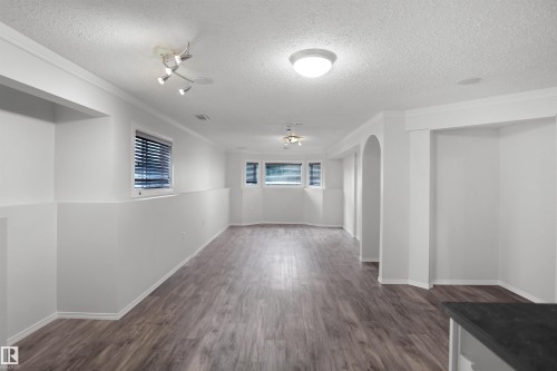 Expansive room featuring wood-finish flooring, multiple windows with blinds, recessed lighting, and an arched doorway - 907 Jordan Crescent Nw, Edmonton, AB - Indoor Photo Showing Other Room