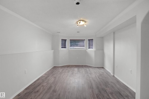 Recessed bay windows with blinds, wood-finish flooring, overhead lighting, and crown molding - 907 Jordan Crescent Nw, Edmonton, AB - Indoor Photo Showing Other Room