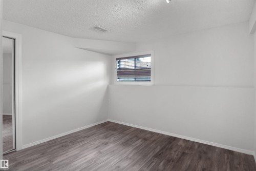 Wood-finish flooring, white painted walls, window with blinds, white trim, and a mirrored closet door - 907 Jordan Crescent Nw, Edmonton, AB - Indoor Photo Showing Other Room