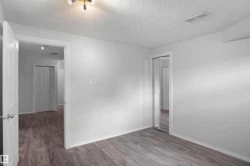 Wood-finish flooring, white walls, and a ceiling light fixture - 907 Jordan Crescent Nw, Edmonton, AB - Indoor Photo Showing Other Room