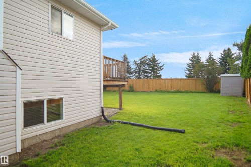 Expansive backyard with a manicured lawn, wood privacy fencing, and a built-in storage shed - 907 Jordan Crescent Nw, Edmonton, AB - Outdoor